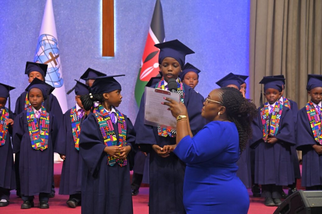 A teacher reading a certificate to a PP2 graduate